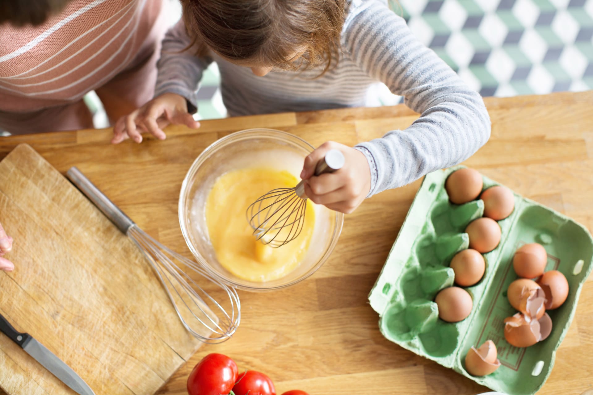 Jente som pisker egg til eggerøre. Foto.