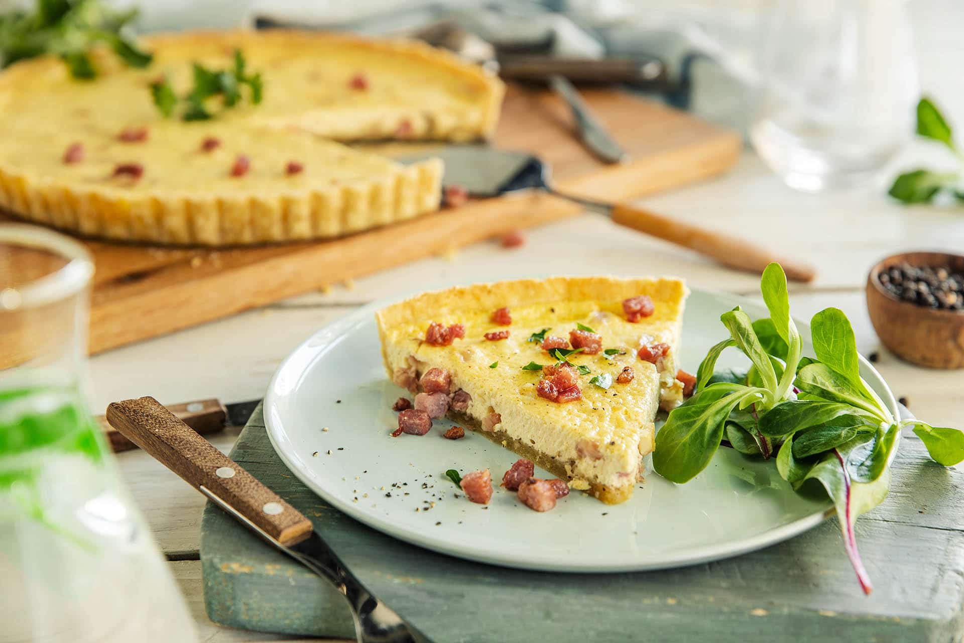 Quiche Lorraine med pai i bakgrunnen og kakestykke foran