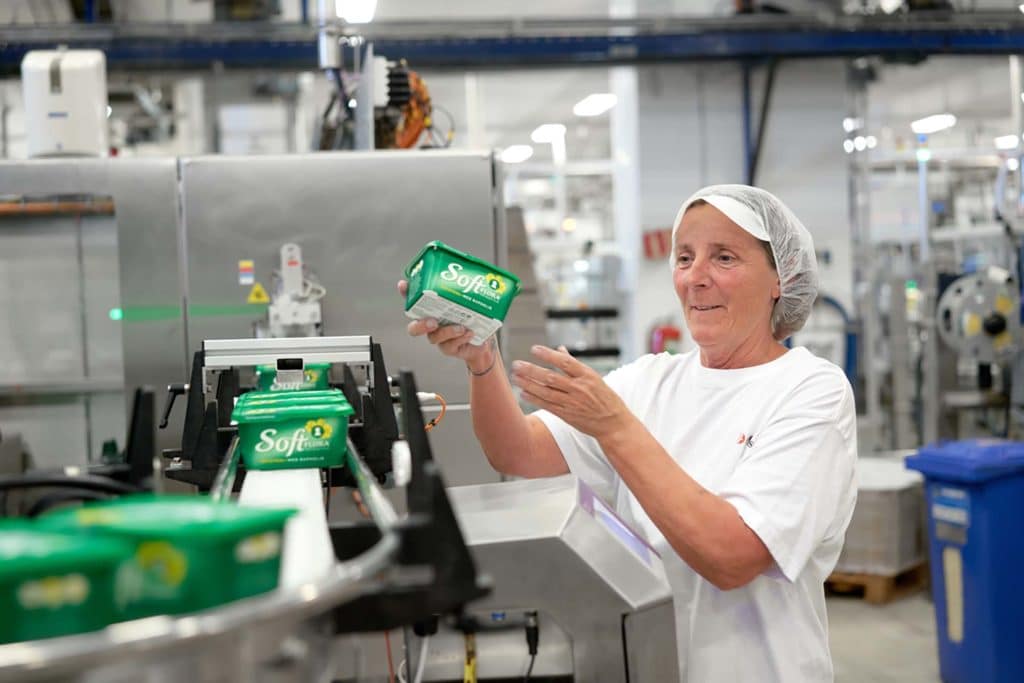 Ansatt i fabrikk inspiserer en boks soft flora