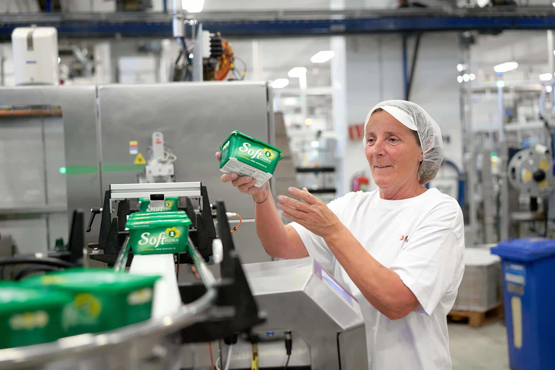 Ansatt i fabrikk inspiserer en boks soft flora