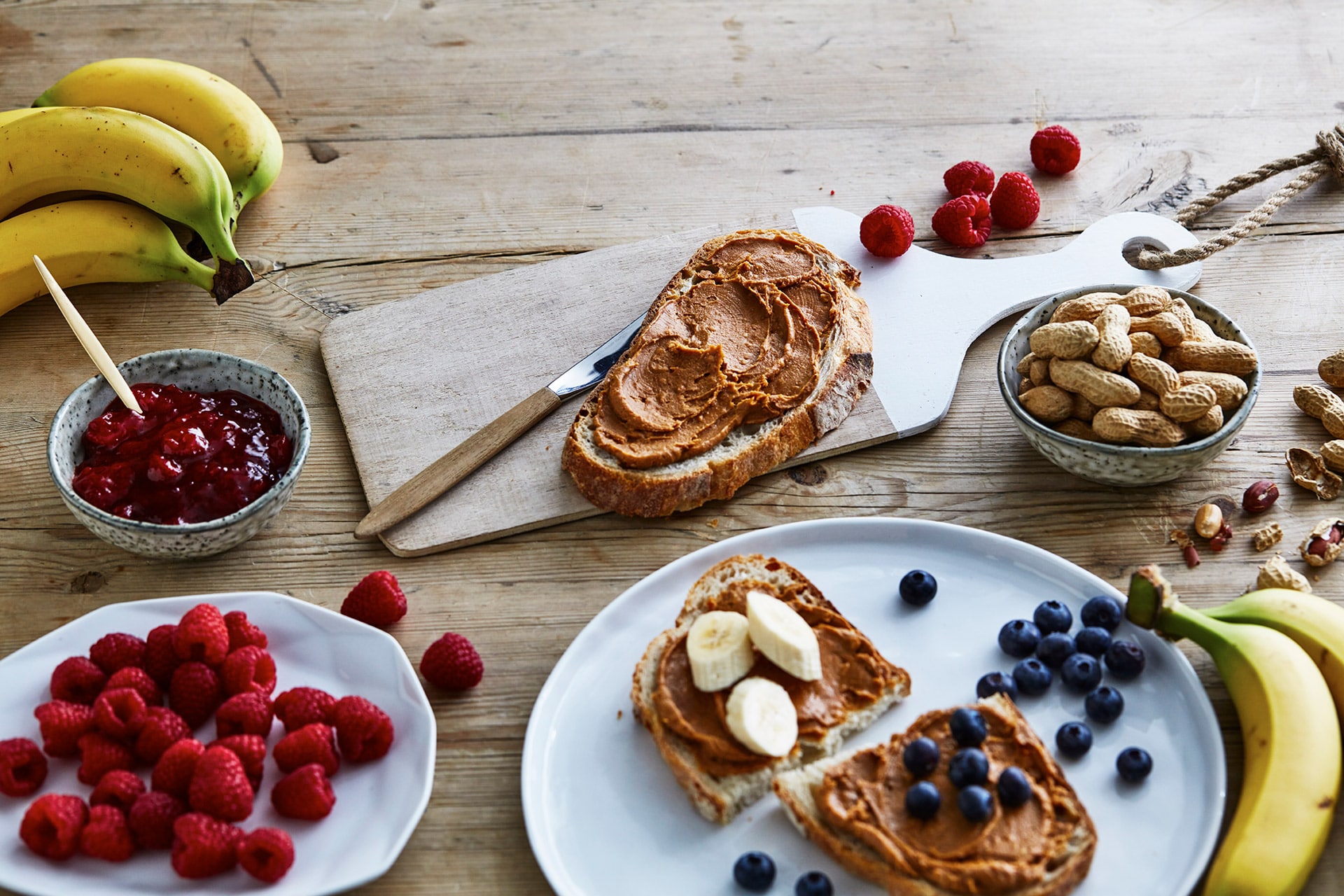 Peanøttsmør på brødskive med frukt og bær. Foto.