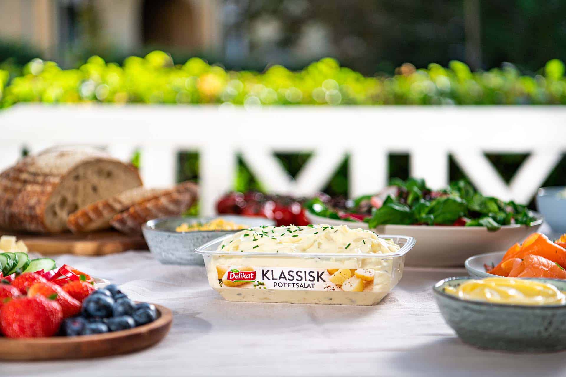 Delikat potetsalat på bord omgitt av grillmat